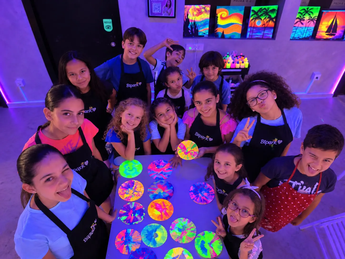 Grupo de niños sonrientes con sus creaciones de colores neón en Bspark, Para tu hijo/a
